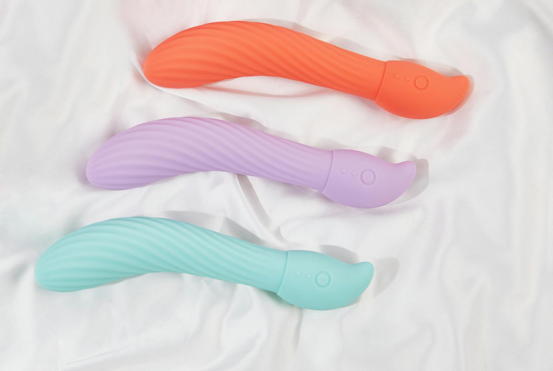 Three colorful vibrators arranged on white fabric