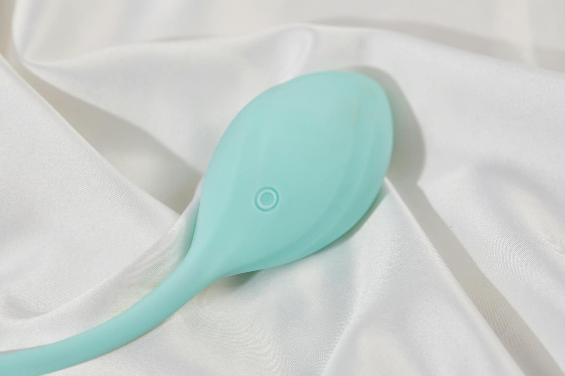 A stylish teal lemon vibrator on smooth white silk fabric