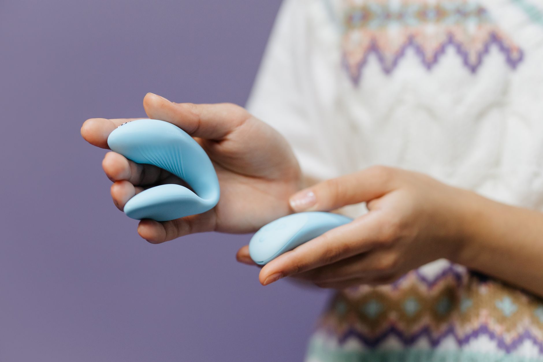 Close-up of hands holding a sleek vibrator together, symbolizing partnership and shared intimacy.