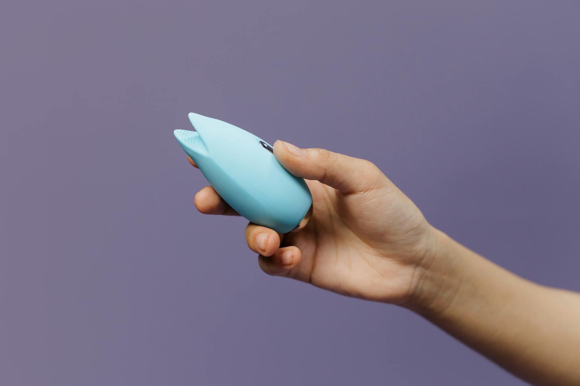 Woman holding a pink vibrator, emphasizing intimate self-connection and personal pleasure.